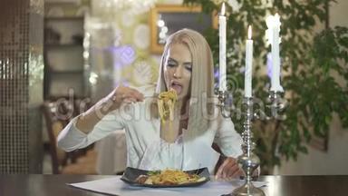 年轻的金发女郎穿着白色夹克，独自一人在<strong>高档餐厅</strong>吃意大利料理做着滑稽的脸